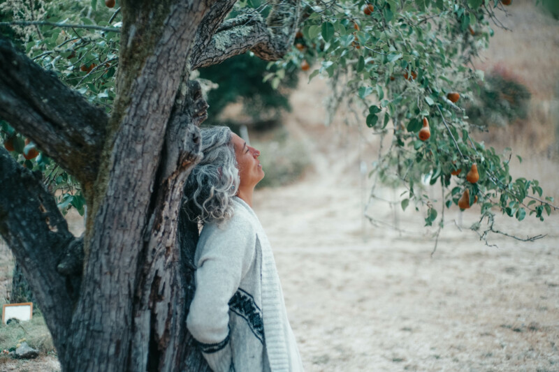 woman standing under tree in silent contemplation.